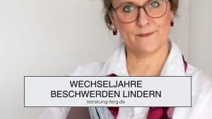 Hormoncoach Heike Ferg mit weißer Bluse, rotem Schal und einem roten Ordner im Arm.